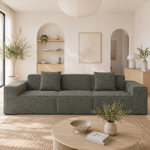 Modern living room with a gray sectional sofa, round wooden coffee table, and decorative elements.