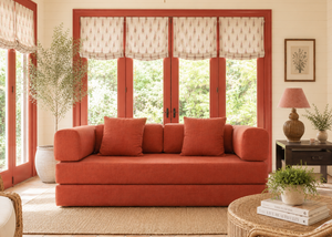 Living room with a red sofa, wicker chair, and large windows.